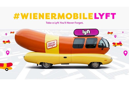 A picture of the Oscar Mayer Weinermobile, which is a vehicle shaped like a hot dog. This includes the signage of the Lyft brand.